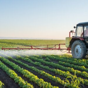 Farmer in a tractor driving through crop field spraying pesticide/herbicide
